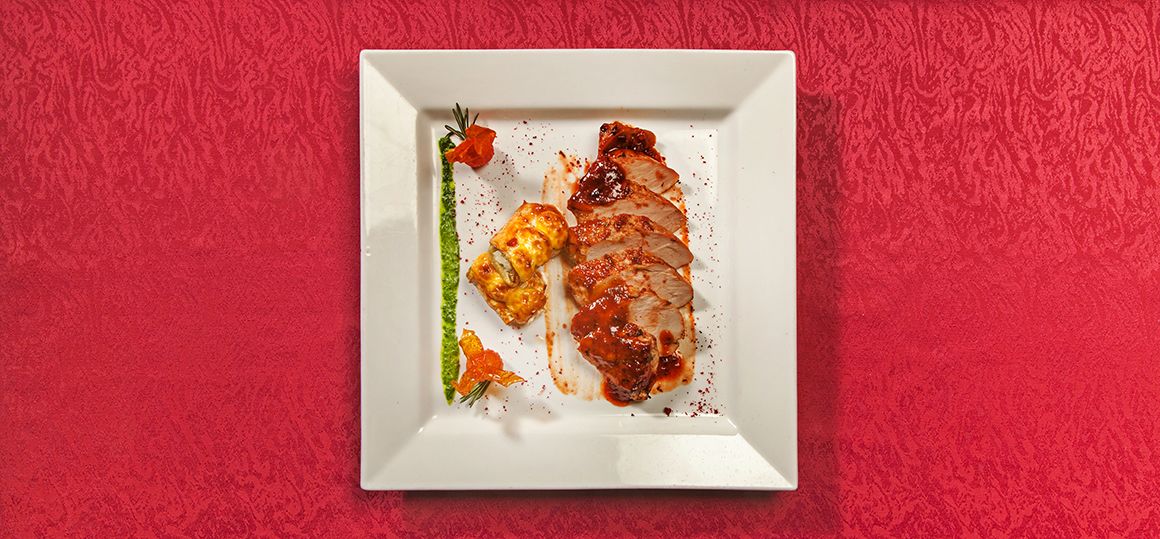 Свиная вырезка жареная под соусом с рулетиками из баклажан и жареными томатами