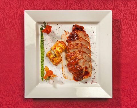 Свиная вырезка жареная под соусом с рулетиками из баклажан и жареными томатами
